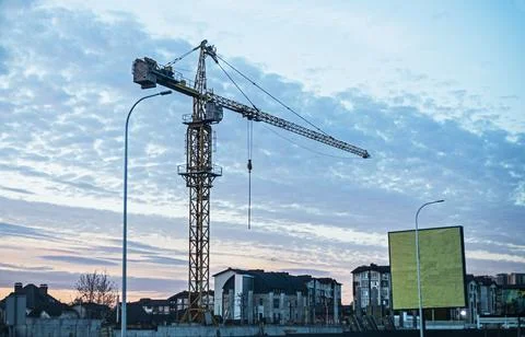 A construction crane against a blue evening sky with clouds Stock Photos