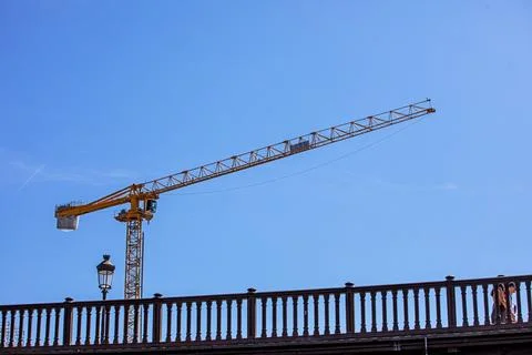 Construction crane against a blue sky near a bridge Stock Photos