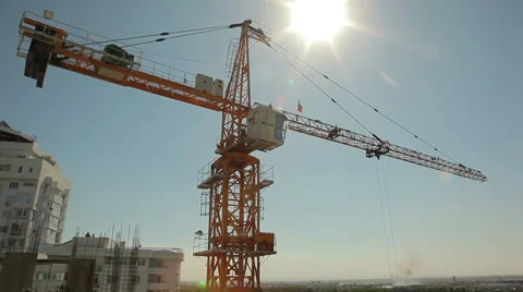 Construction crane against a bright sun and blue sky Видео 38549872