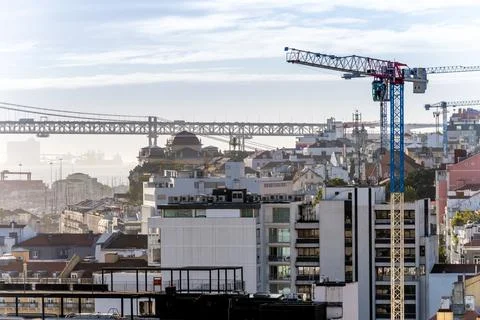 Construction crane and bridge over Lisbon rooftops Stock Photos