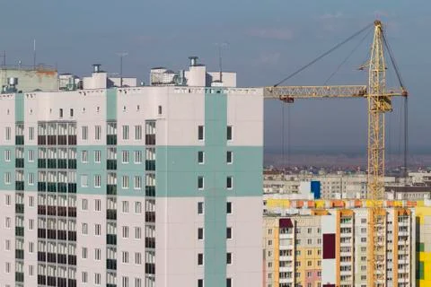 Construction crane and built multi-storey residential building Stock Photos