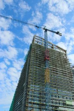 Construction crane and skyscraper under blue sky with clouds Stock Photos