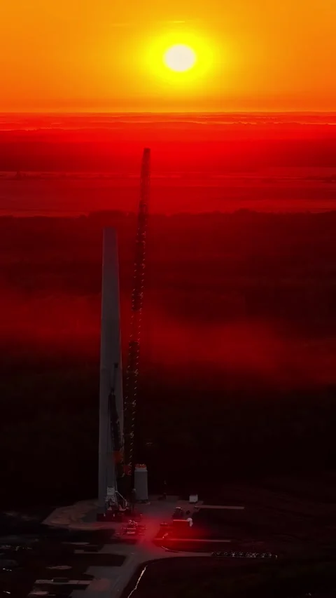 Construction Crane and Tall Structure Silhouetted Against Dramatic Red Sunset Stock Footage 336238350