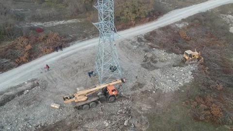 Construction crane and tractor install power pylon in cloudy weather aerial shot Stock Footage 231711028
