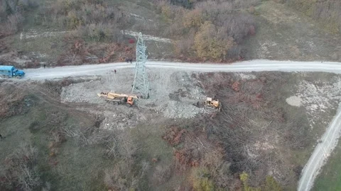 A construction crane and a tractor install a power line in the mountains in Stock Footage 231711147