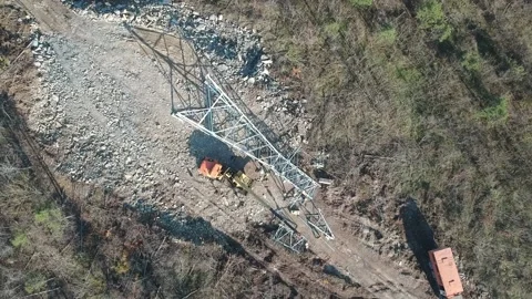 A construction crane and a tractor install a power line an orange truck is Stock Footage 231711941