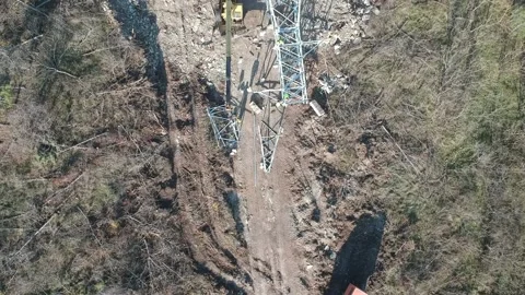 A construction crane and a tractor install a power line an orange truck is Stock Footage 231714267