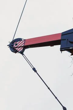 A construction crane arm extends upward as workers prepare for heavy lifting  Photos