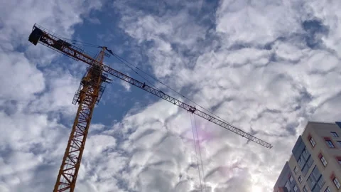 Construction crane on the background of a beautiful sky with clouds and sun Stock Footage 253413991