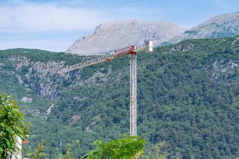 Construction crane on a background of green mountain Stock Photos