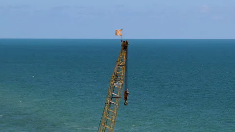 Construction Crane Boom with Flag Above Calm Ocean Stock Footage 346502310