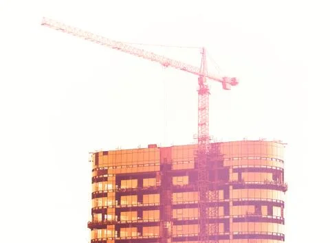 Construction crane building skyscraper during sunset Stock Photos