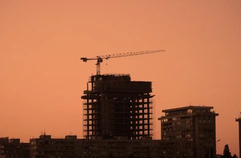 Construction crane building a skyscraper at sunset Stock Photos