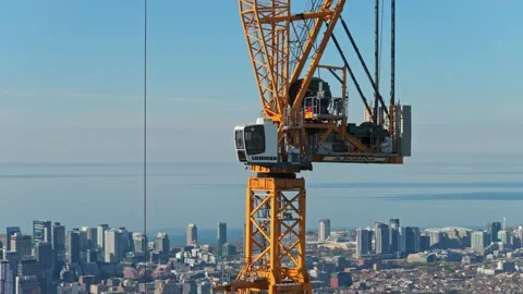 Construction crane cabin operating over downtown area with city skyline in backg Stock Footage 334696974