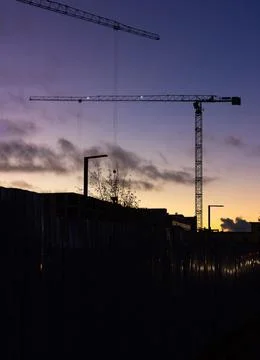 Construction crane in the city while working in new buildings. Evening city l Stock Photos