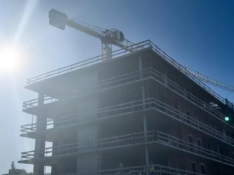 Construction crane during the construction of a residential building at sunse Stock Photos