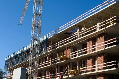 Construction crane during the construction of a residential building at sunse Stock Photos