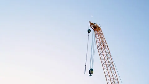 Construction crane gently swaying in front of crescent moon at twilight Stock-Footage 97143000