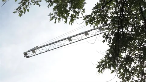 Construction crane high in sky with blue sky clouds behind, tip pointing out Stock Footage 251354765