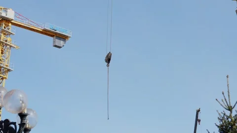 Construction crane hook hanging over a building site under sky Stock Footage 332431483