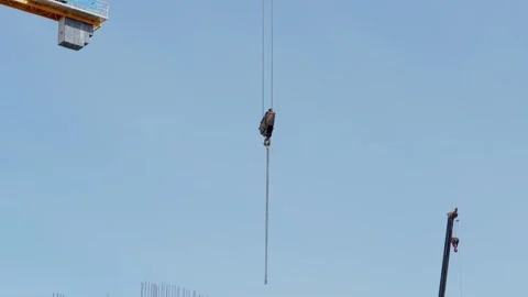 Construction crane hook hanging over a building site under sky Stock Footage 332431492