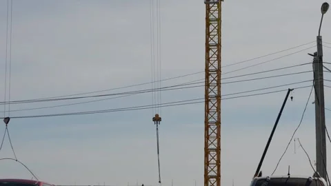 Construction crane hook hanging over a building site under sky Stock Footage 332431500