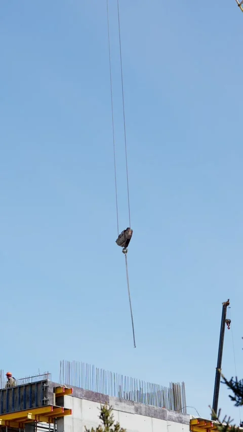 Construction crane hook hanging over a building site under sky Stock Footage 332431530