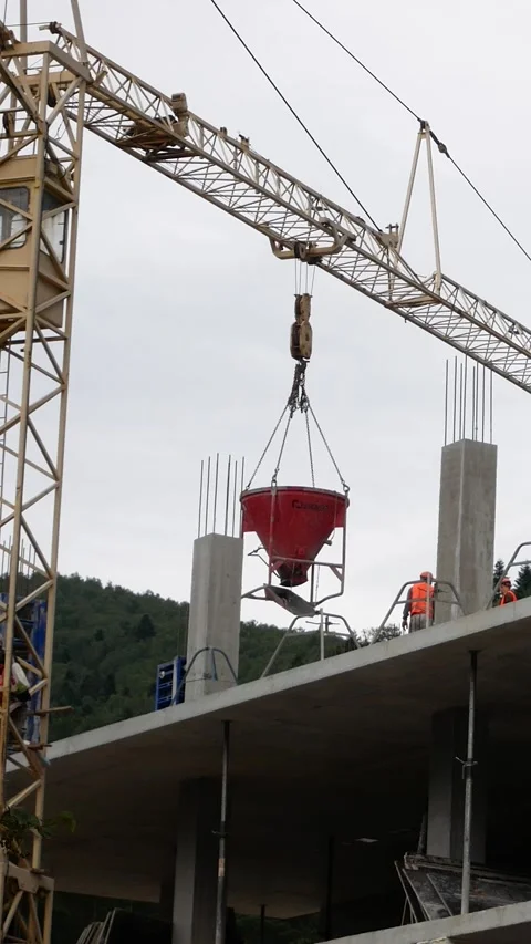 Construction Crane Lifting Concrete Container to Upper Floor of Building Stock-Footage 346525948