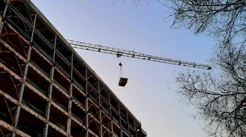 Construction crane lifting heavy load at building site. Fotos Stock