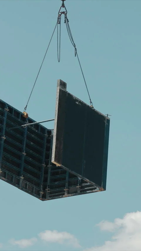 Construction crane lifting large panel on building site. A crane is seen lifting Stock Footage 308538608