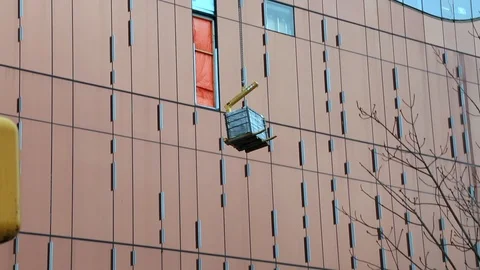 Construction crane lifting load modern building facade Stock Footage 98569497