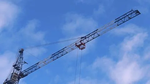 Construction crane lifting materials against a blue sky with clouds, showca.. Stock Photos
