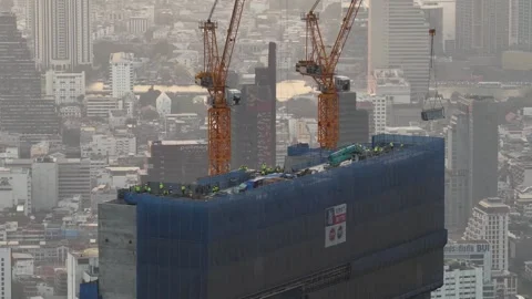 Construction crane lifting materials atop skyscraper 스톡 동영상 328489930