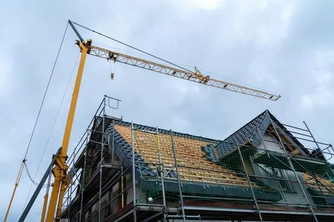 Construction crane lifting materials to a building under renovation Stock Photos
