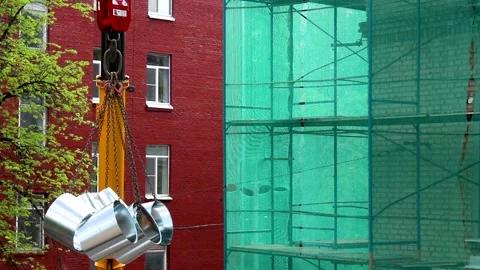 Construction crane lifting metal pipes near red brick building Stock Footage 341833940