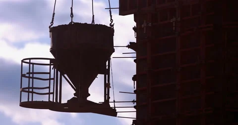 A construction crane lifts a bucket of cement to the top of building  Stock Footage 147633677