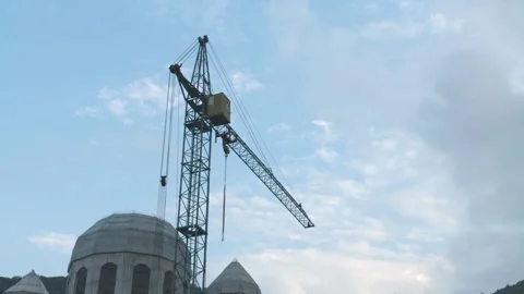 Construction crane lifts heavy materials near domed buildings Stock Footage 341745131