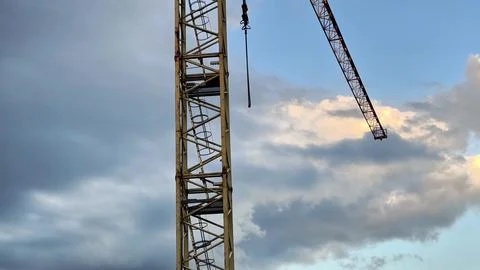 A construction crane operates against a dramatic sky, symbolizing urban dev.. Stockfoto's