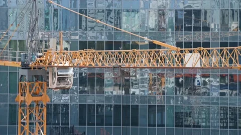 Construction crane operation in front of a modern glass building Stock Footage 131127745