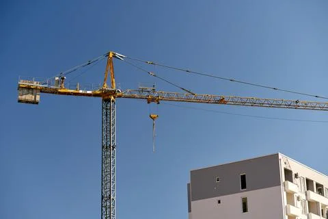 Construction crane over a finished block of flats against a blue sky background 스톡 사진