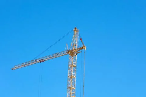 A construction crane is positioned high above a construction site. It reaches Stockfoto's