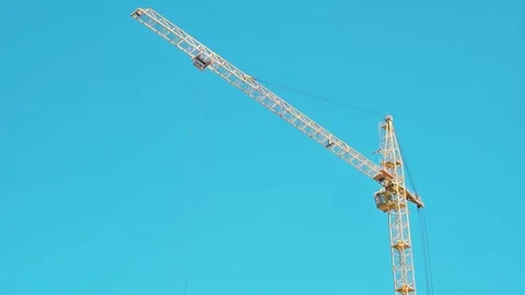 A construction crane is seen moving and lifting materials in the air against a Stock Footage 339090590