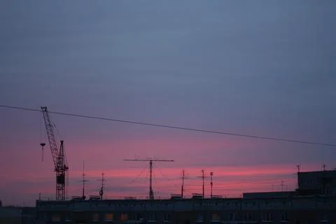 Construction crane silhouette under dark blue and pink twilight sky Stock Photos