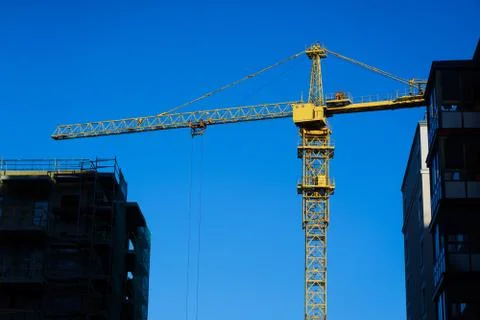 Construction crane on the sky background among buildings Stock Photos