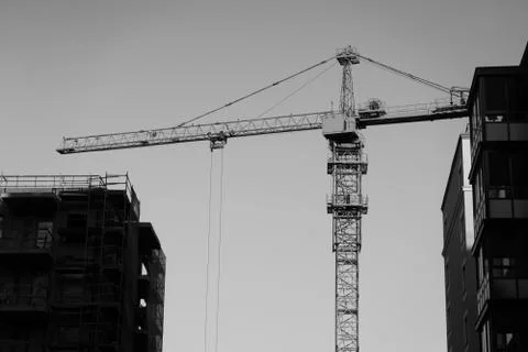 Construction crane on the sky background among buildings Stock Photos
