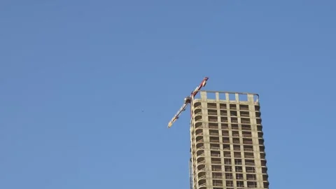 Construction crane on skyscraper under construction against blue sky Stock Footage 283814284