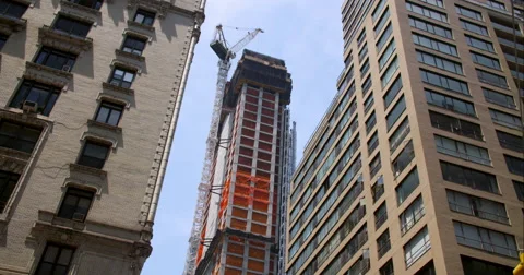 Construction crane slow moves rotates between New York City skyscrapers Stock Footage 67290813