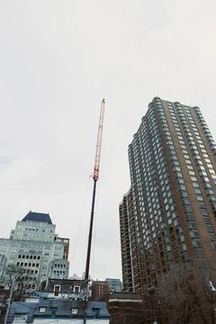Construction crane stands tall between buildings in an urban setting during.. Stock Photos