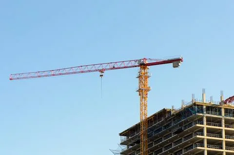 Construction crane stationary at low angle view of building under construct.. Stock Photos