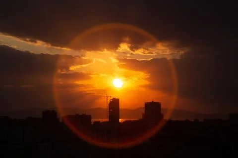 Construction crane at sunset on a background of orange sun, a city by the sea Stock Photos